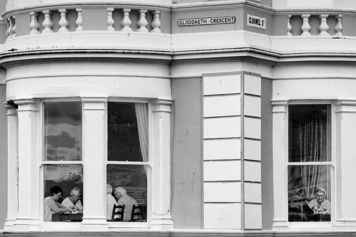 Persone sedute dietro le vetrate di un caff&egrave;, fotografia di Roberto Lugano