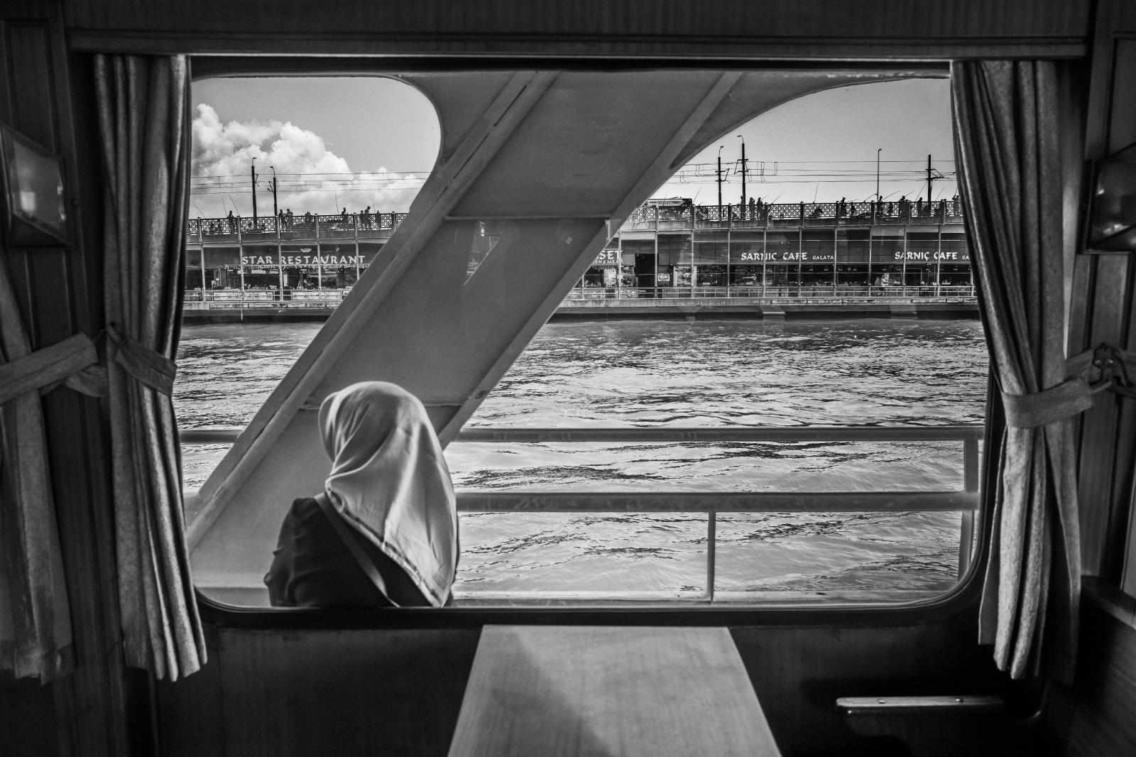 Una donna con il velo guarda il fiume dal finestrino di un battello, fotografia di Roberto Lugano