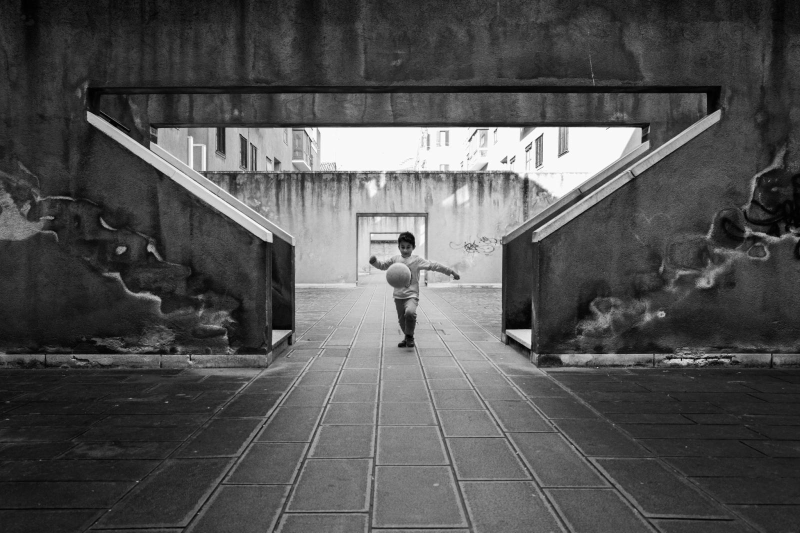 Un bambino con un pallone in un sottopassaggio, fotografia di Roberto Lugano