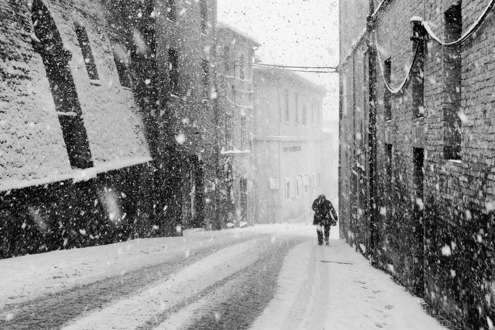 Una persona cammina in una strada sotto la neve, fotografia di Roberto Lugano
