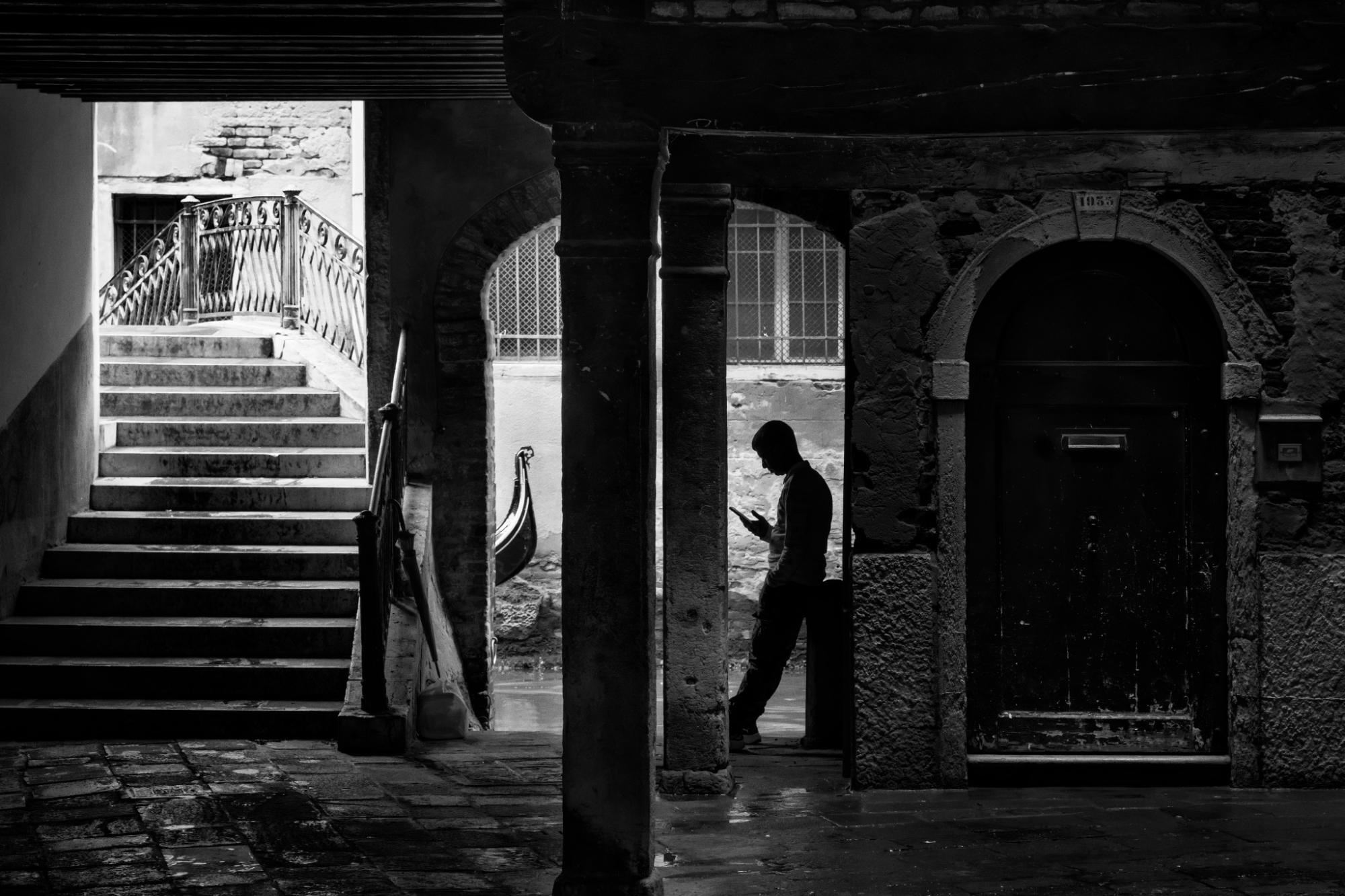 Un uomo al telefono nella penombra di un portico, fotografia di Roberto Lugano