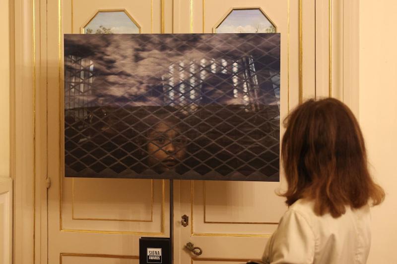 Una visitatrice davanti a una fotografia allestita su una porta