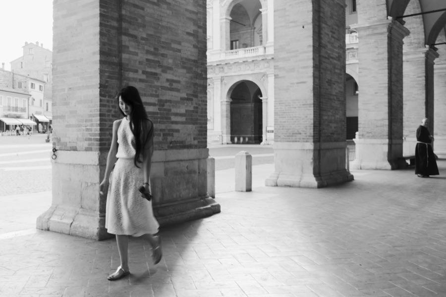 Una donna cammina sotto un portico, fotografia di Roberto Lugano
